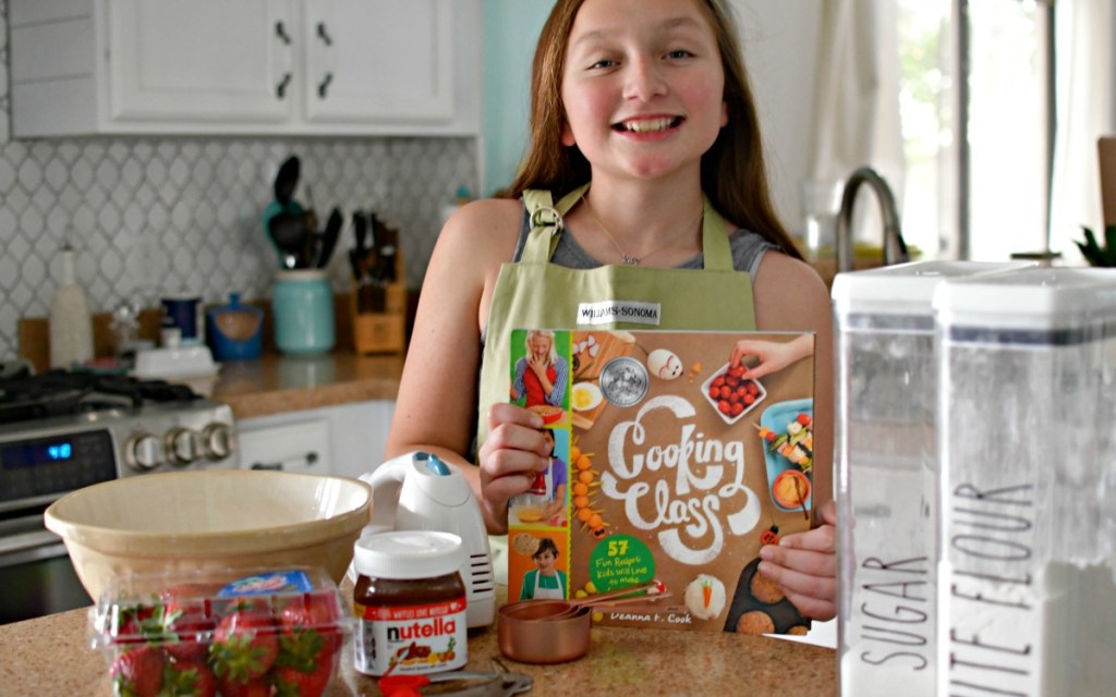girl holding cooking class book