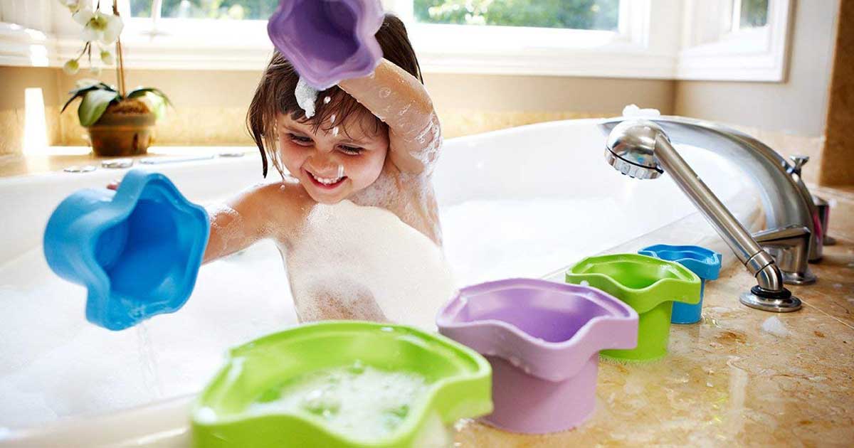 little girl playing in a bubble bath with stacking cups