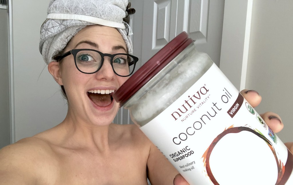 woman holding a jar of coconut oil with towel and glasses on head