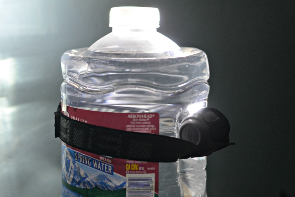 black strap wrapped around headlamp and empty water jug