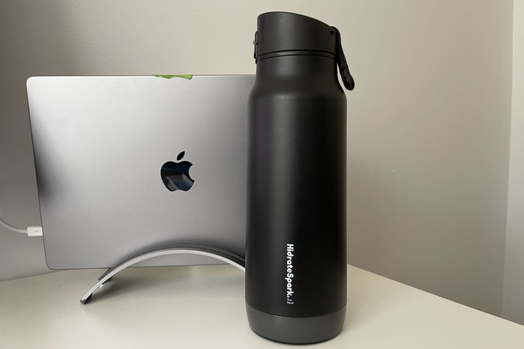 black hidrate water bottle sitting in front of silver mac 