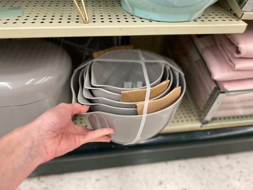5 piece nested mixing bowls on store shelf with human hand pulling them out slightly 