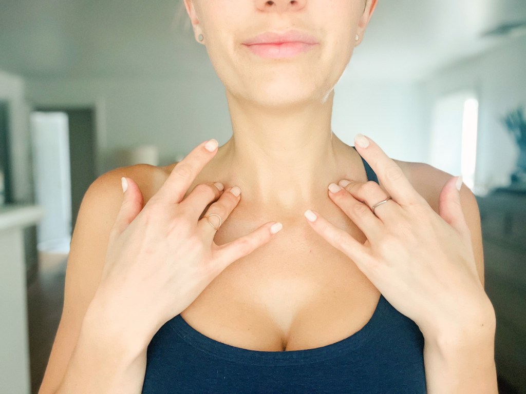 woman putting hands on collar bone pressure points