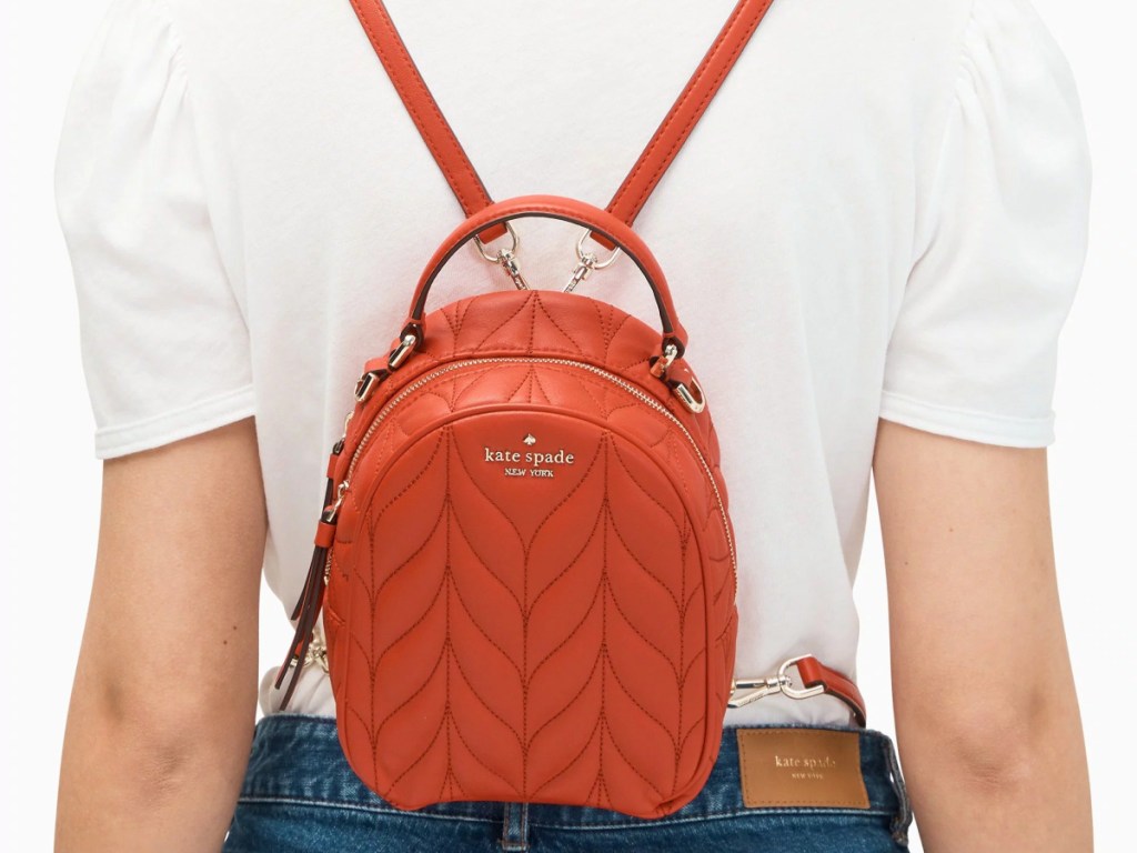 red orange kate spade backpack on woman with white shirt