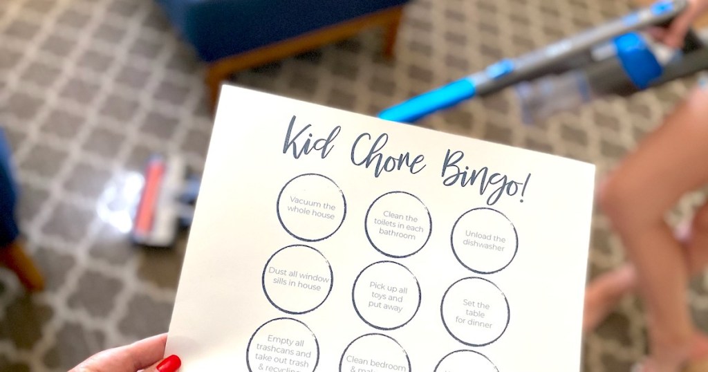 hand holding a white paper with house cleaning tips bingo cleaning game on it