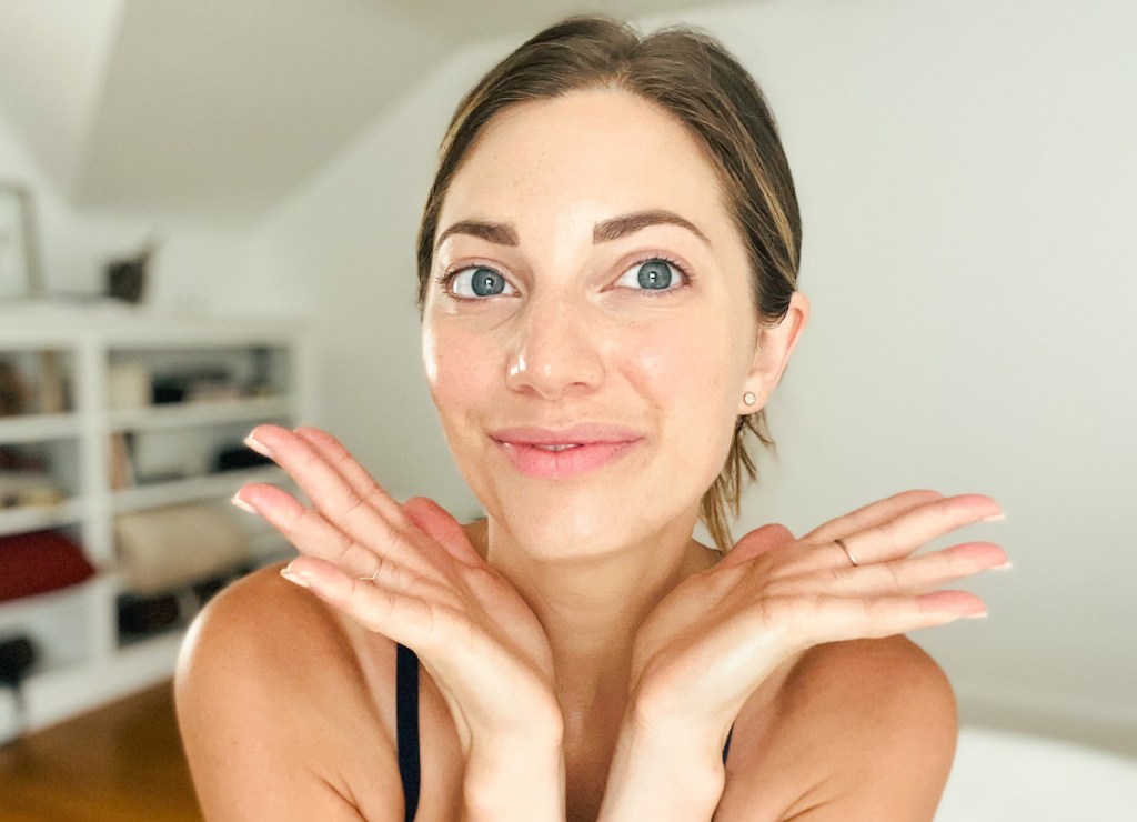 woman showing off glowing face with hands out to side before and after lymphatic drainage massage