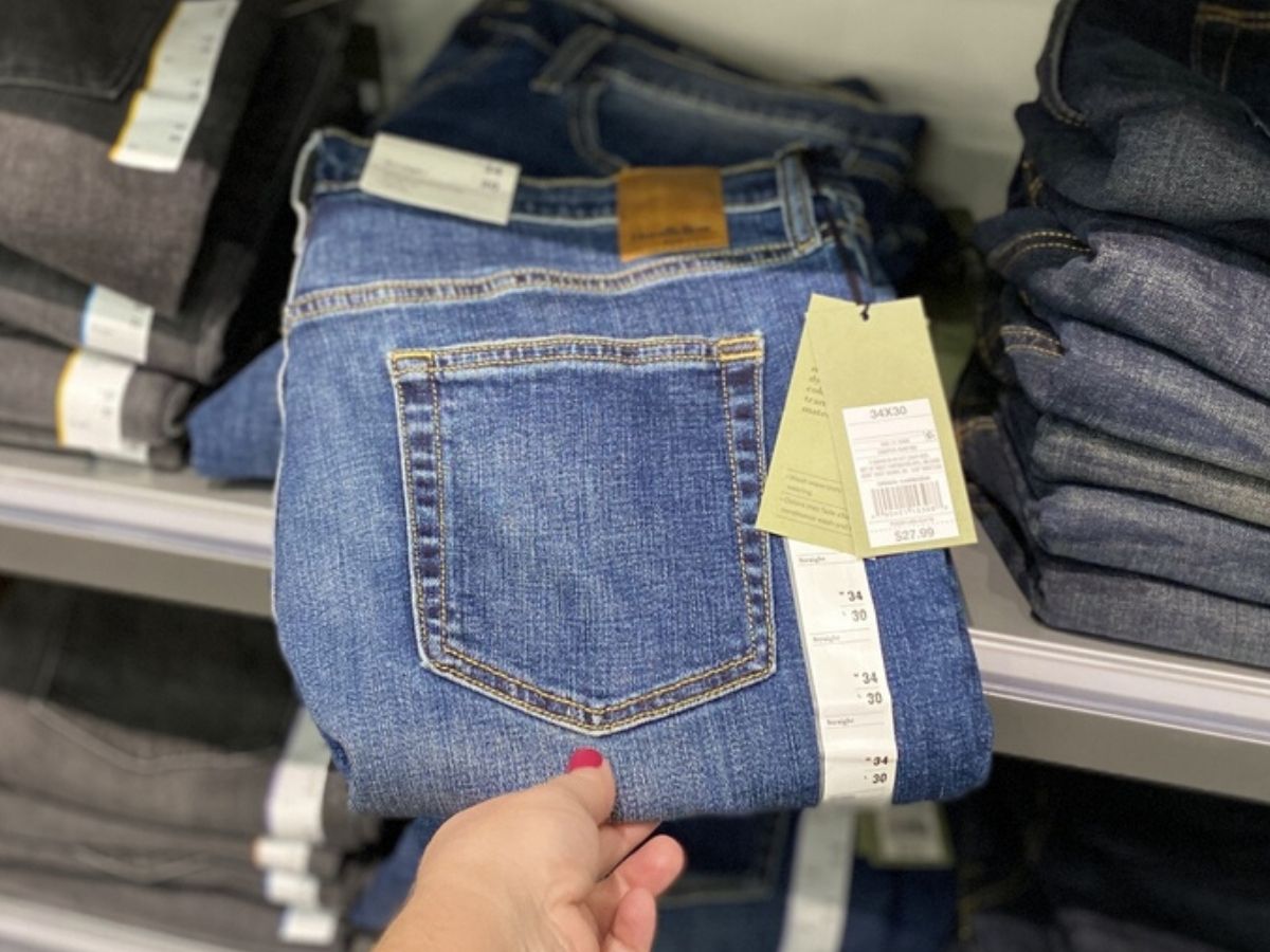woman's hand holding men's folded jeans at store