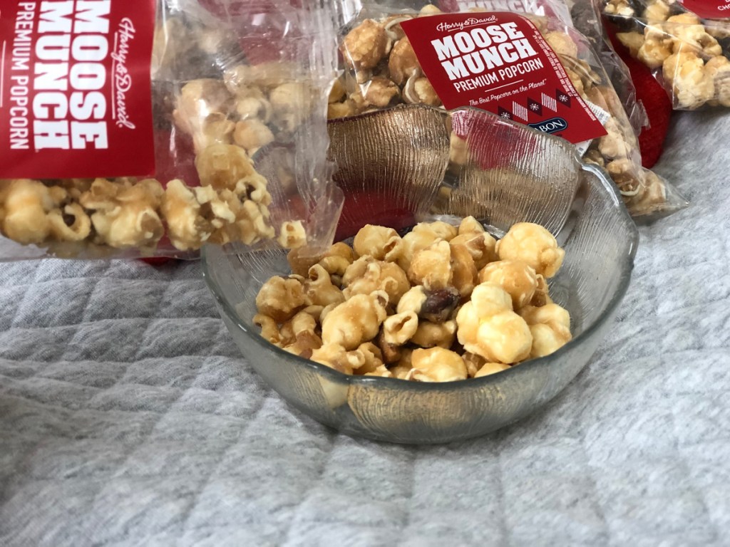 hand pouring moose munch popcorn into bowl from bag