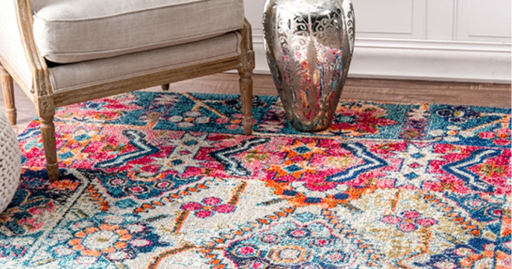colorful rug on a wooden floor with a chair and a vase on it