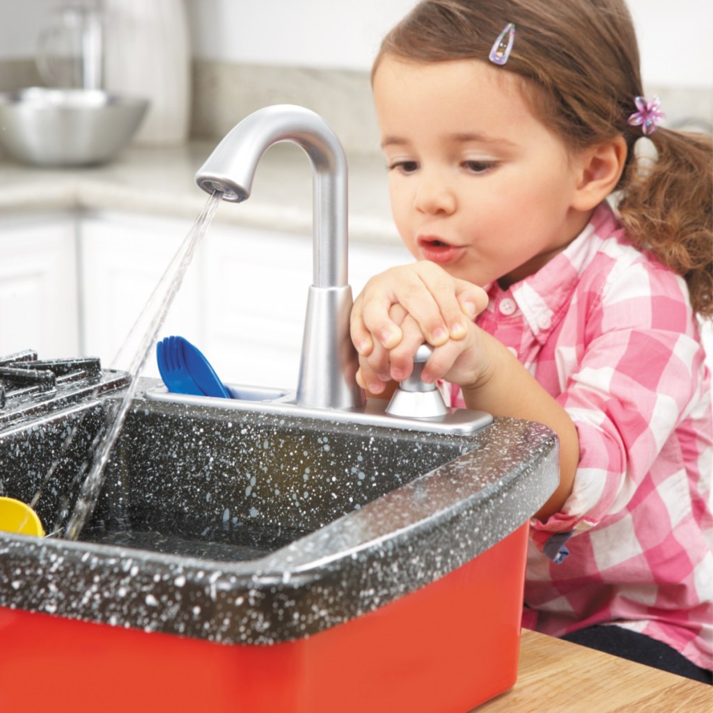little girl pressing the handle on a little tikes splish splash sink 