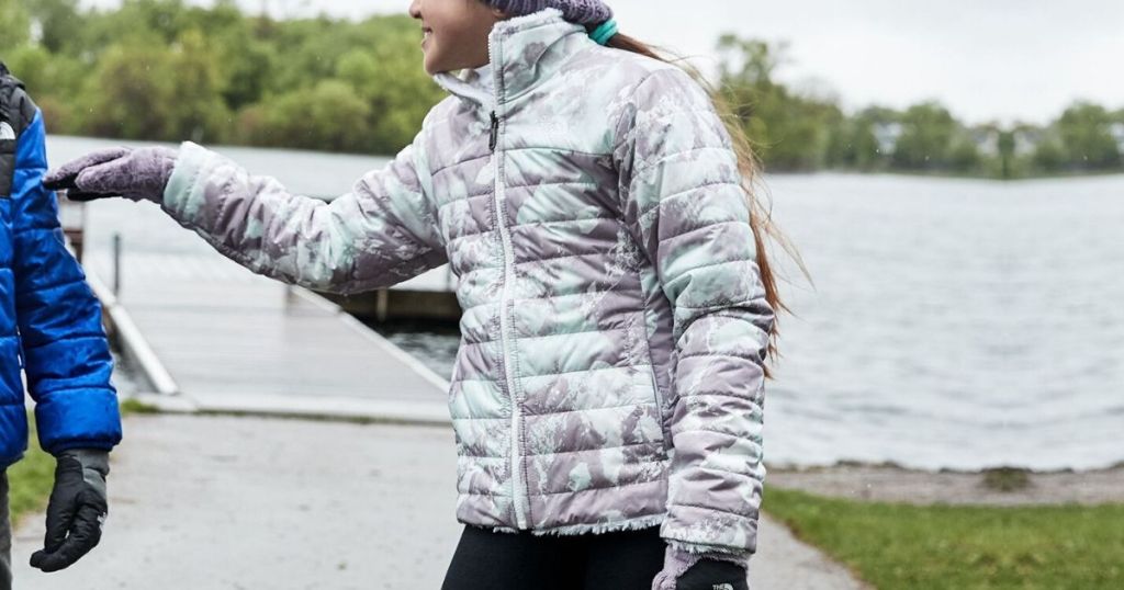 girl wearing puffy winter jacket on dock near water