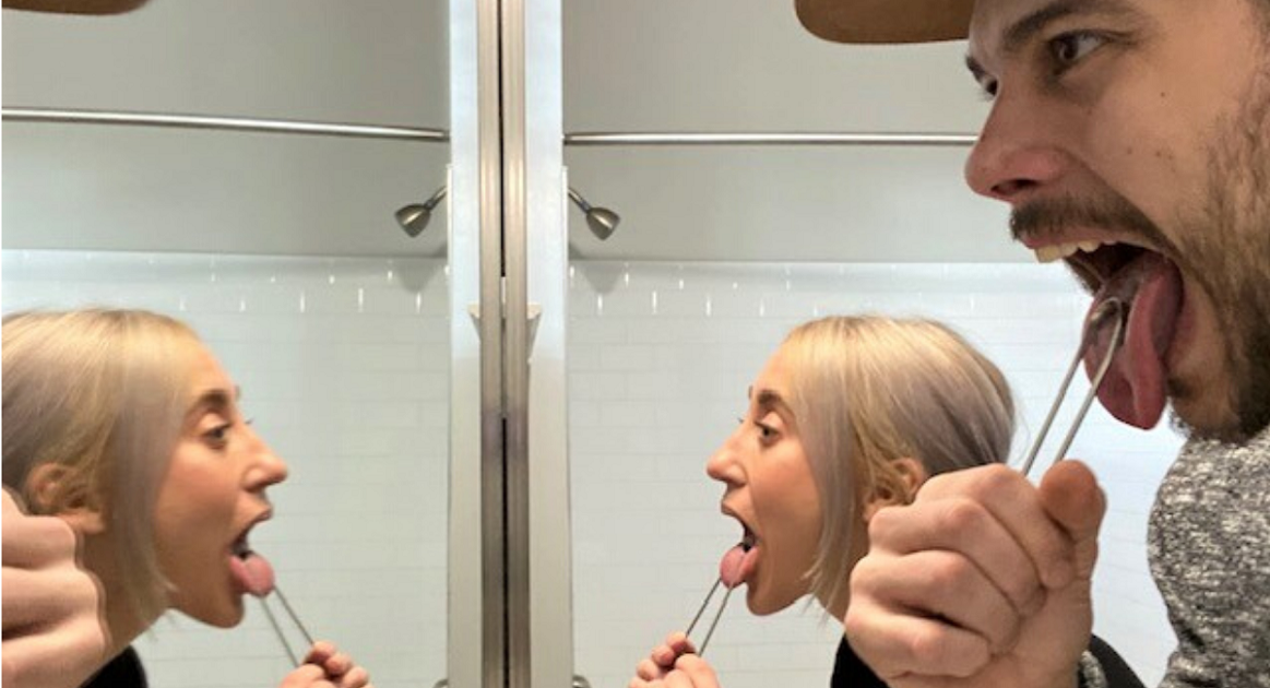 Couple tongue scraping in bathroom mirror