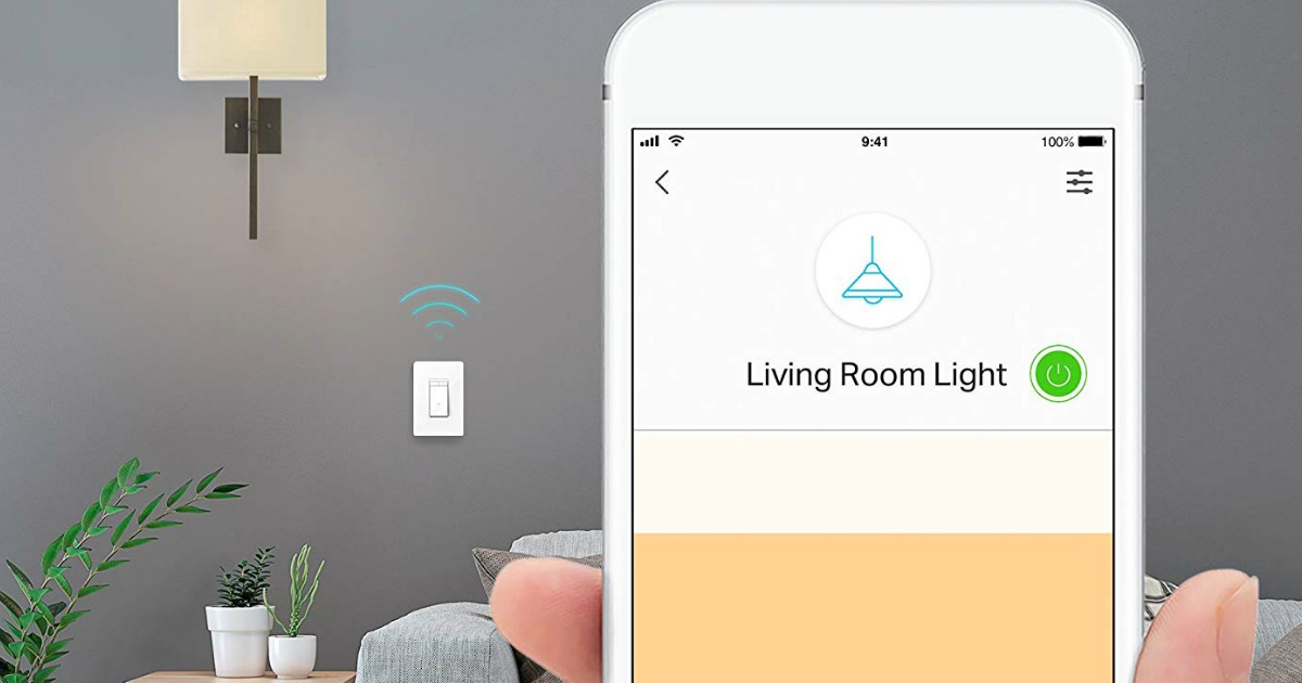 hand holding cell phone in front of dimmer switch and light
