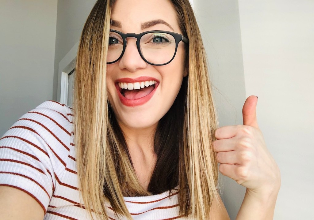 woman smiling giving a thumbs up wearing glasses