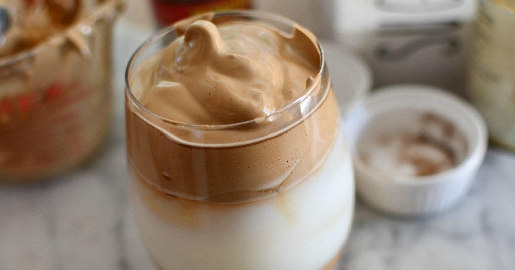 close up of clear glass cups holding whipped iced coffee and milk