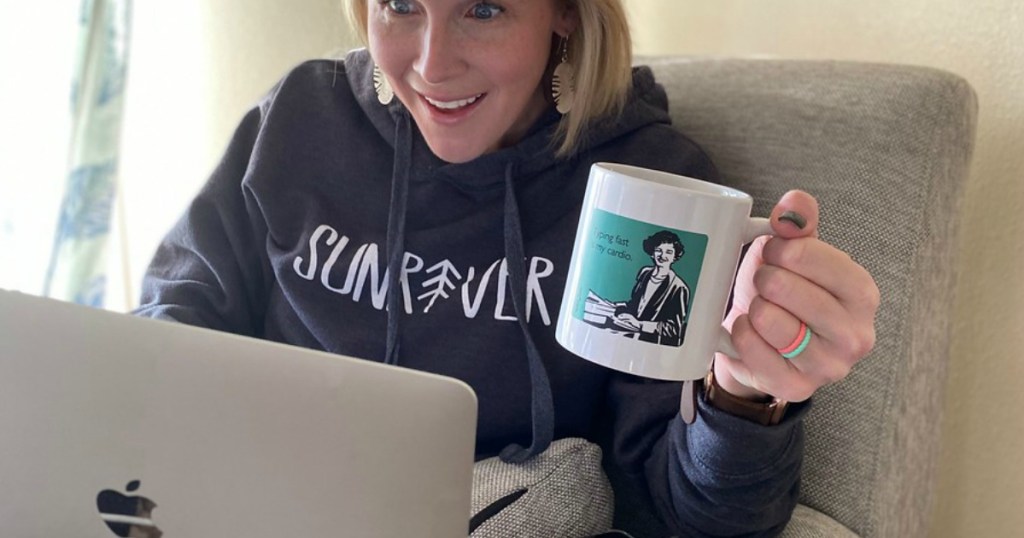 woman holding coffee mug looking at laptop 