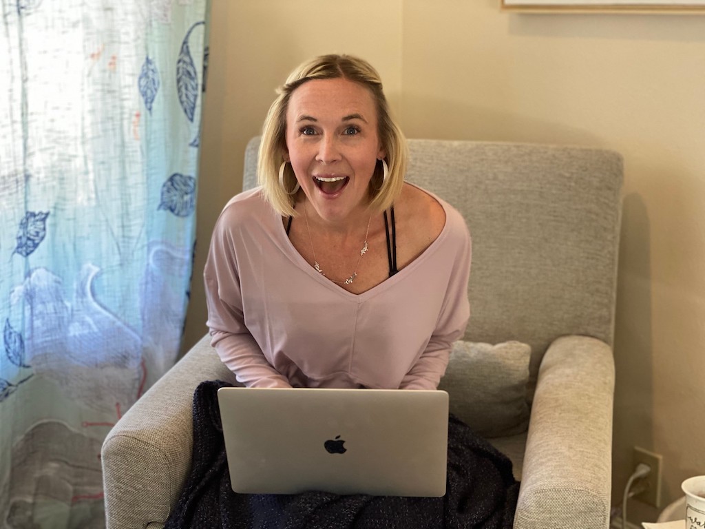woman with Macbook on lap and smile on face