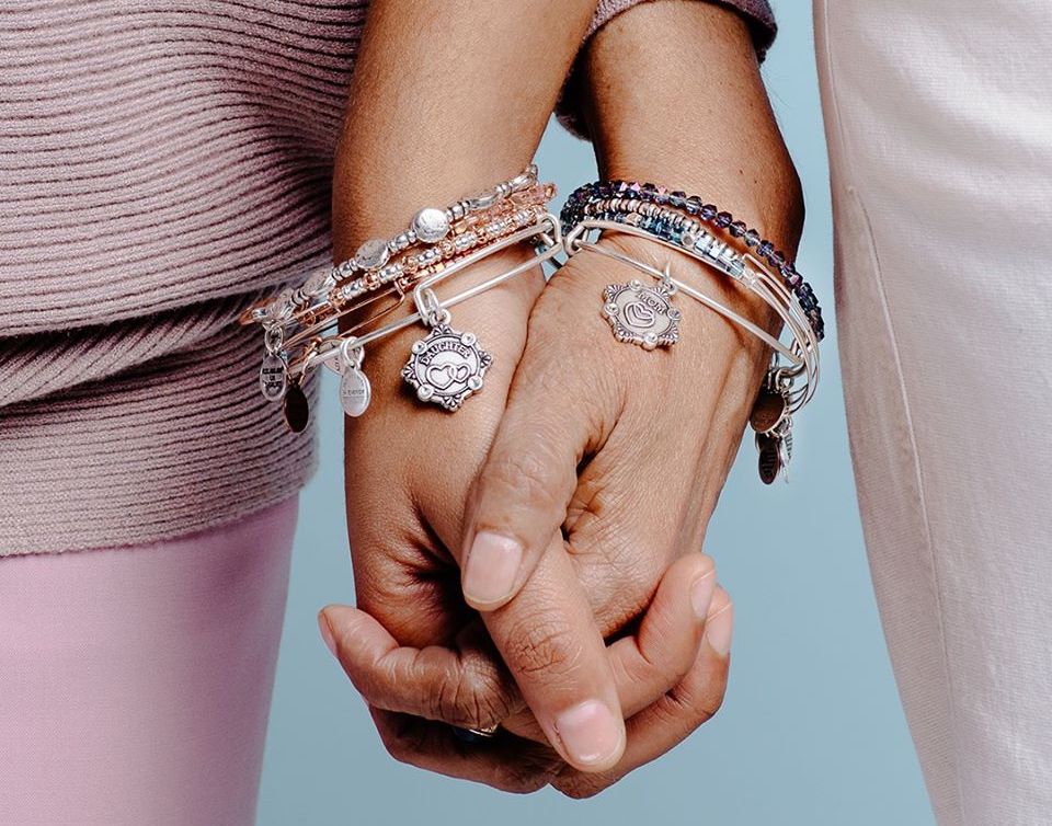 two people holding hands wearing bracelets