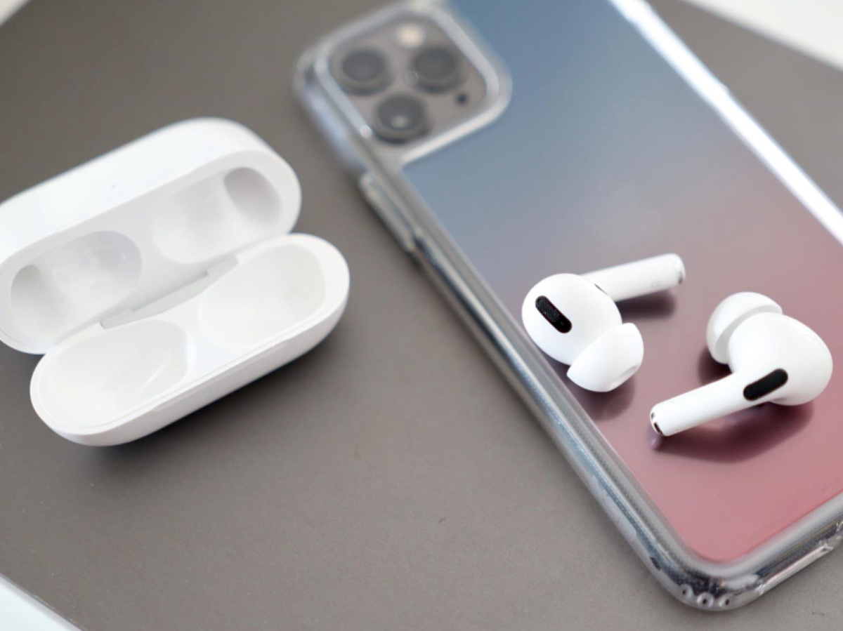 white cordless earbuds on cell phone and charging case on table