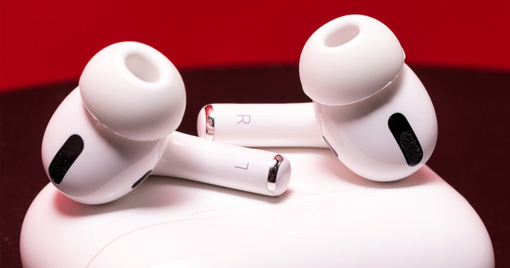 white cordless earbuds on top of white charging case and red background
