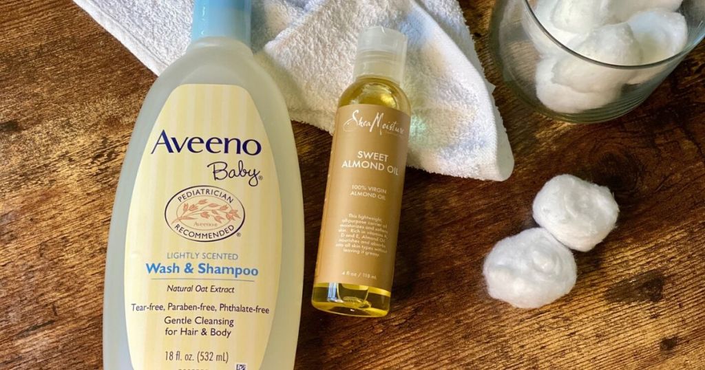 Tear-free baby shampoo and almond oil with cotton balls on a table