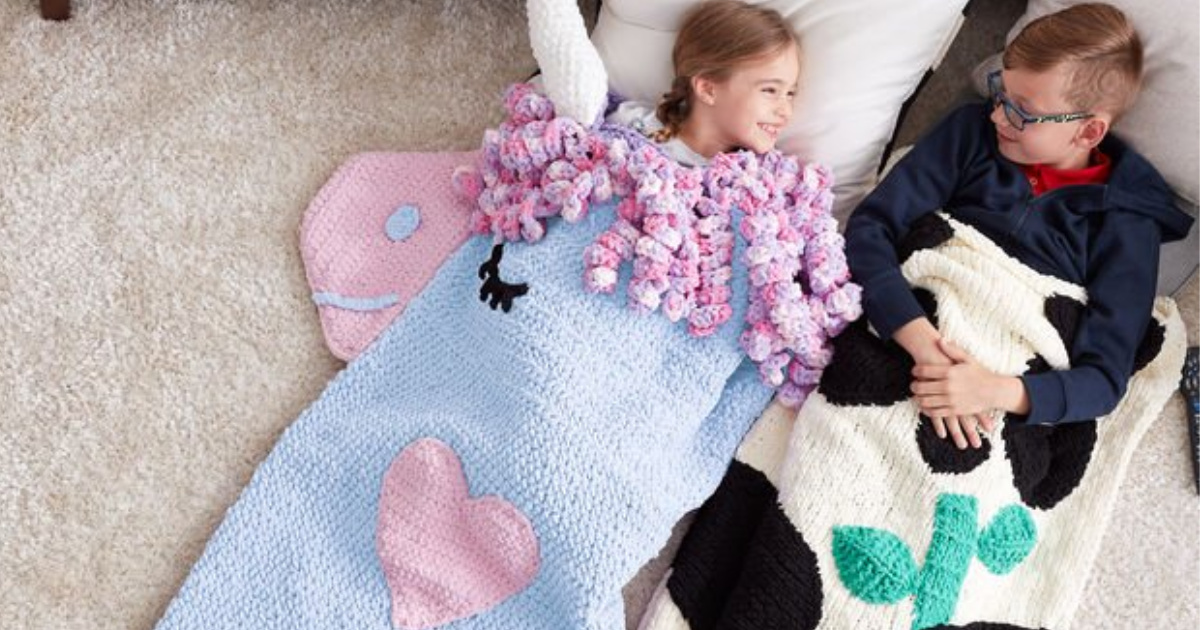 Children laying in a knit unicorn blanket and black and white blanket