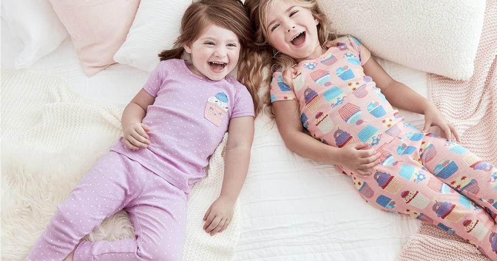 two girls laying on a bed wearing cupcake printed pajama sets
