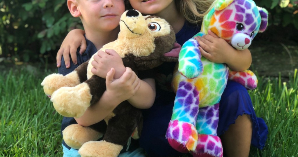 children holding Build-A-Bear stuffed animals outside in grass