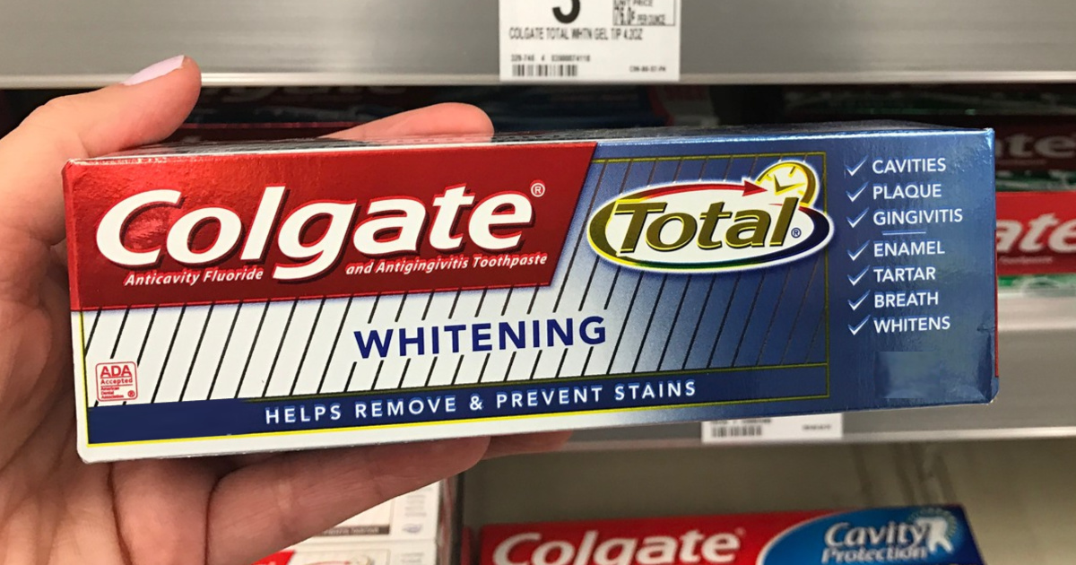 hand holding box of toothpaste in store aisle