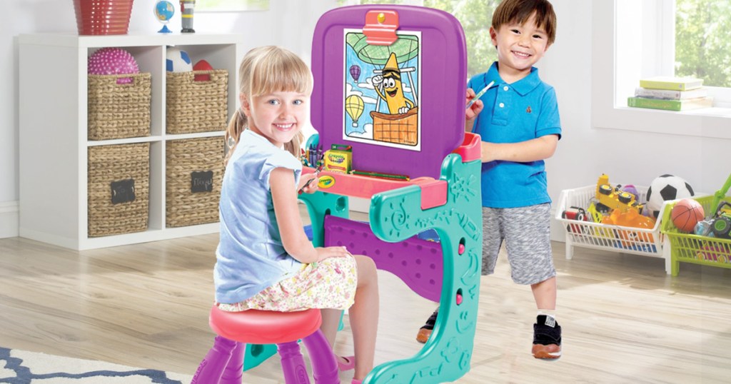 two kids coloring on an art easel in a playroom