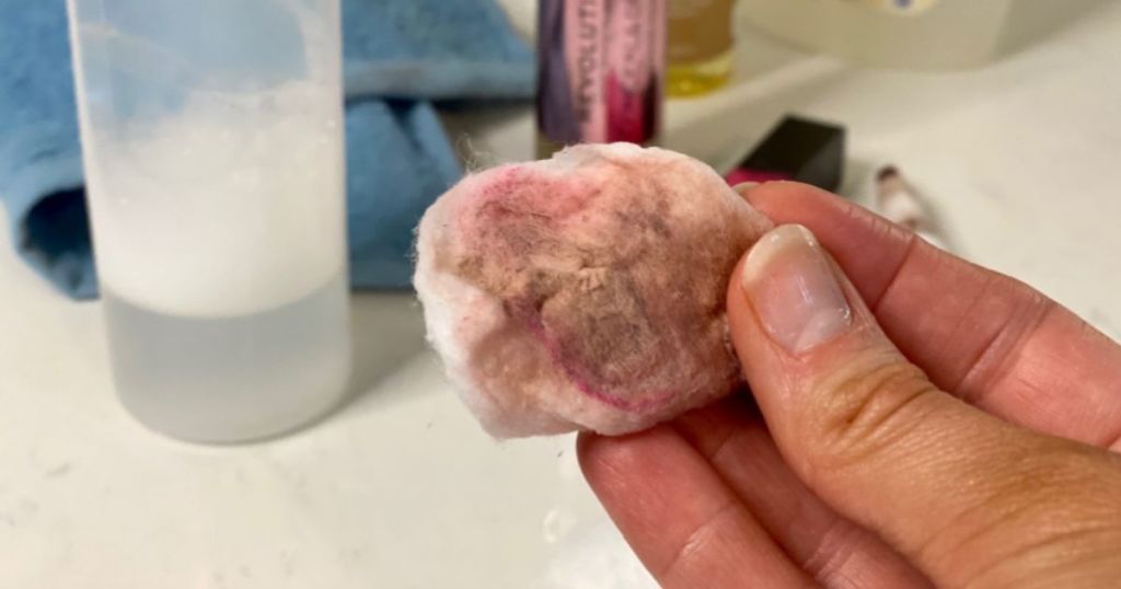 Hand holding a dirty cotton ball with makeup on it after using DIY makeup remover