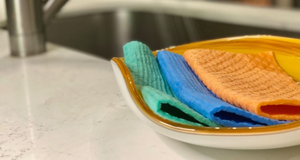 Solid colored Swedish Dishcloths sitting in a bowl next to the kitchen sink