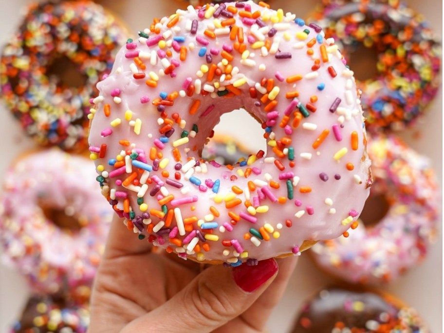 Person holding pink sprinkled donut