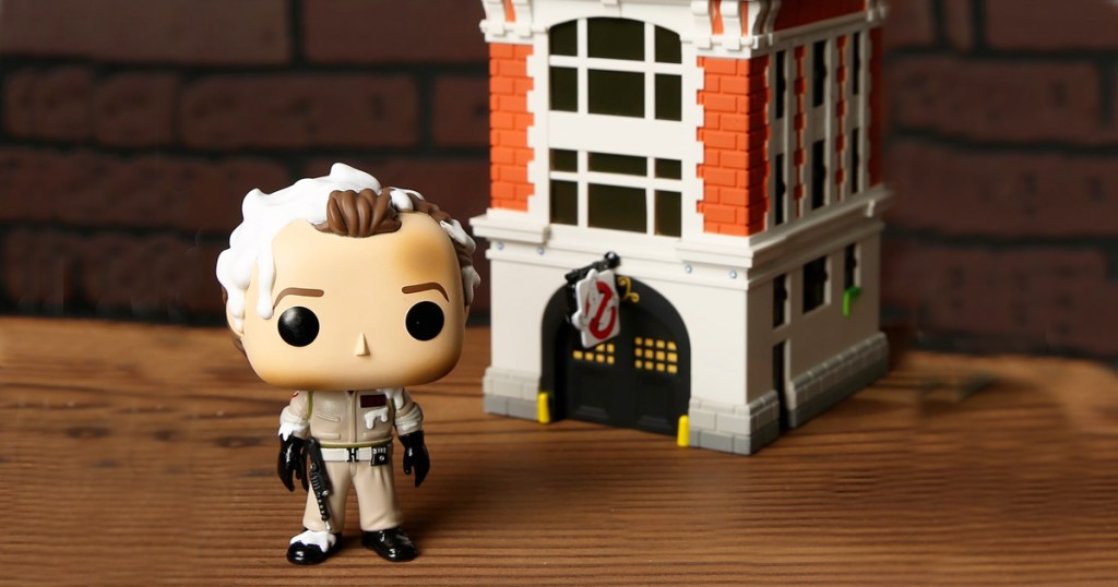 funko pop ghostbusters dr venkman and firehouse toy set on wooden table