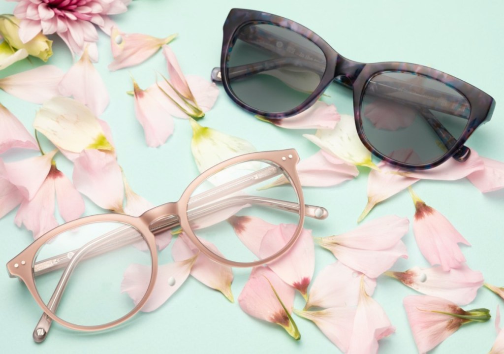 two pairs of glasses on pink background with flowers and flower petals