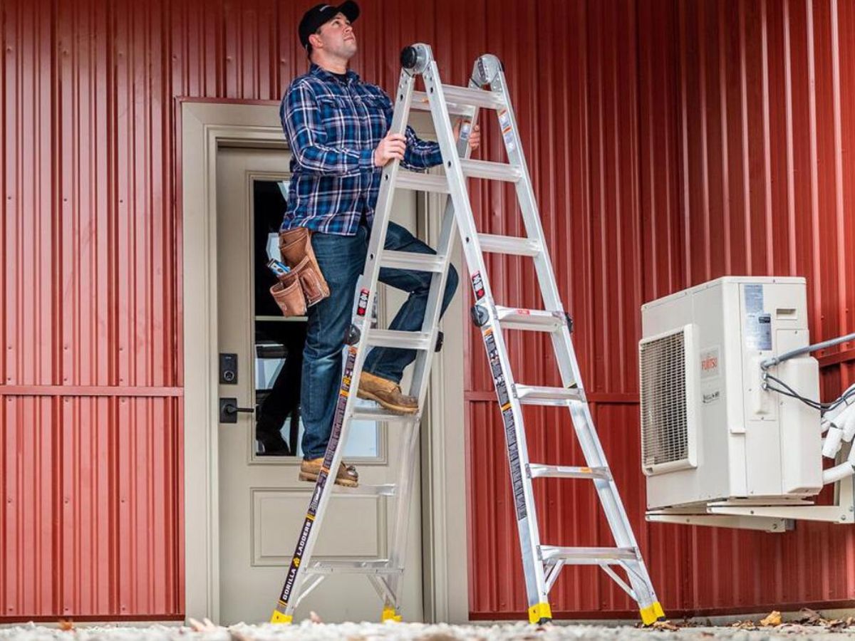 man at the top of an 18 foot ladder in front of a shed