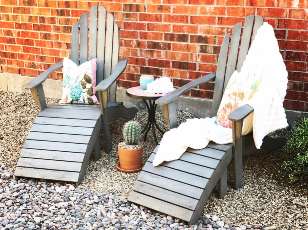 two grey Adirondack chairs in front of brick wall outside