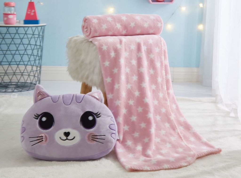 cat pillow next to chair with a blanket on it