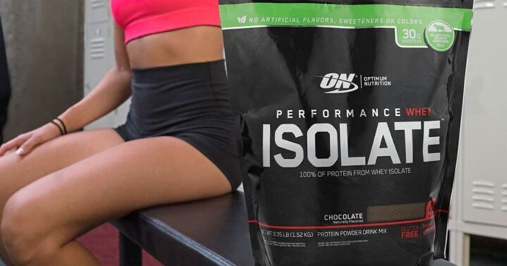 Woman sitting on bench in gym locker room behind bag of protein powder