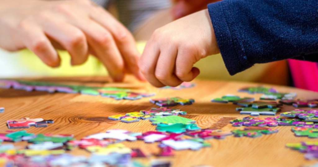 people putting together jigsaw puzzle on wooden table