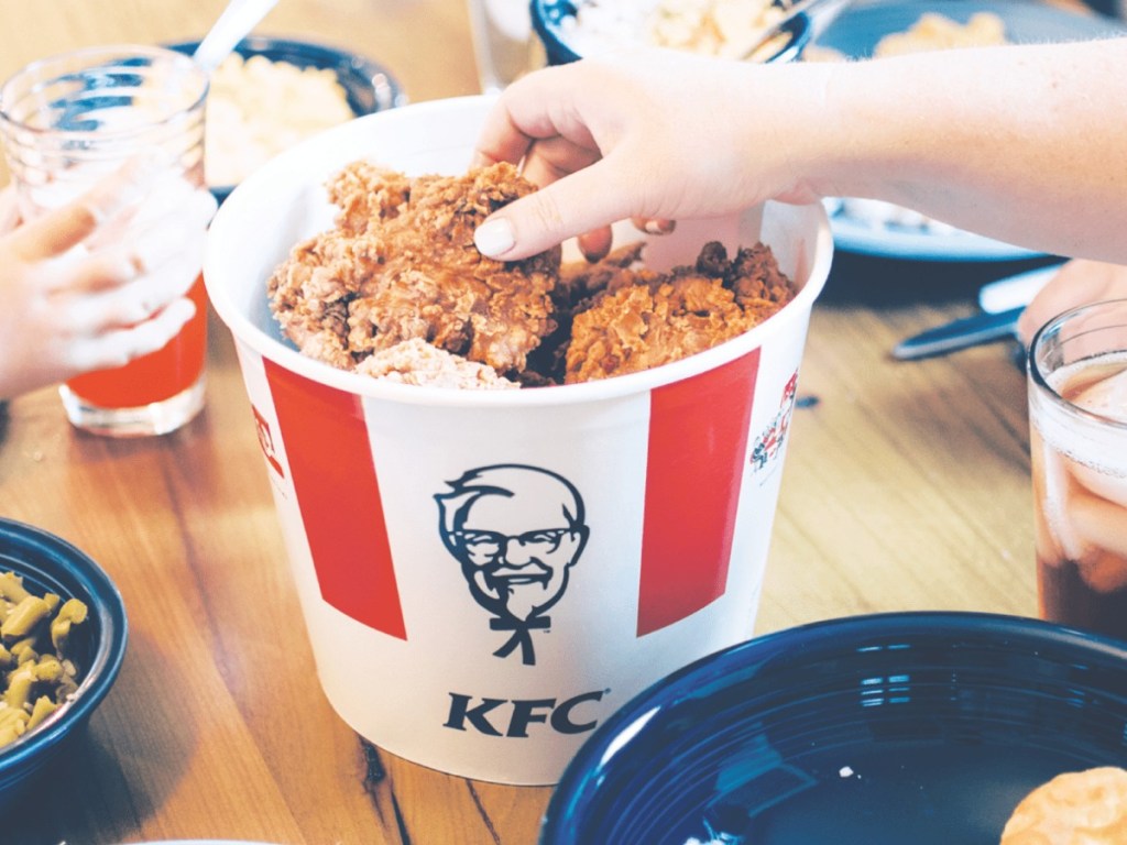 Person grabbing piece of chicken from KFC bucket