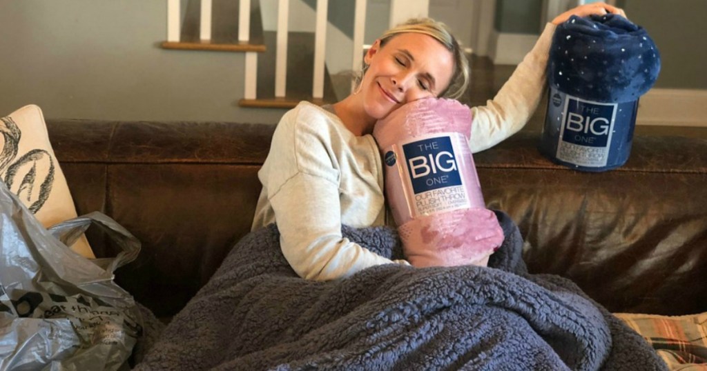 Woman on couch holding Kohl's Big One Throws and smiling