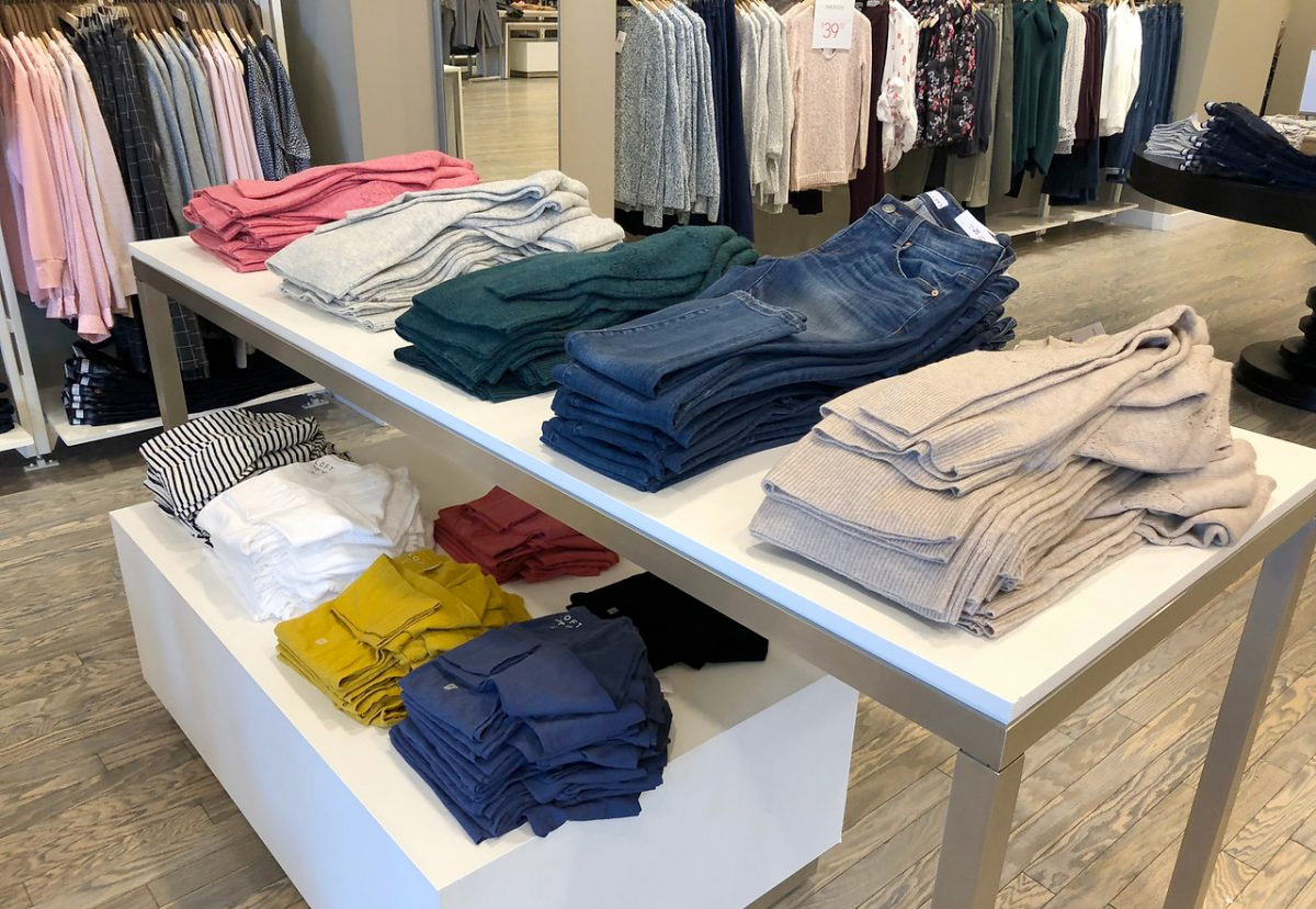 store display table with womens jeans, sweaters, and shirts