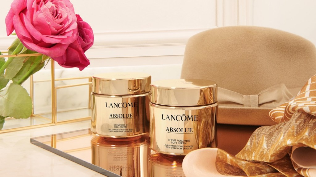 two Lancome creams on a tray by a hat and flower