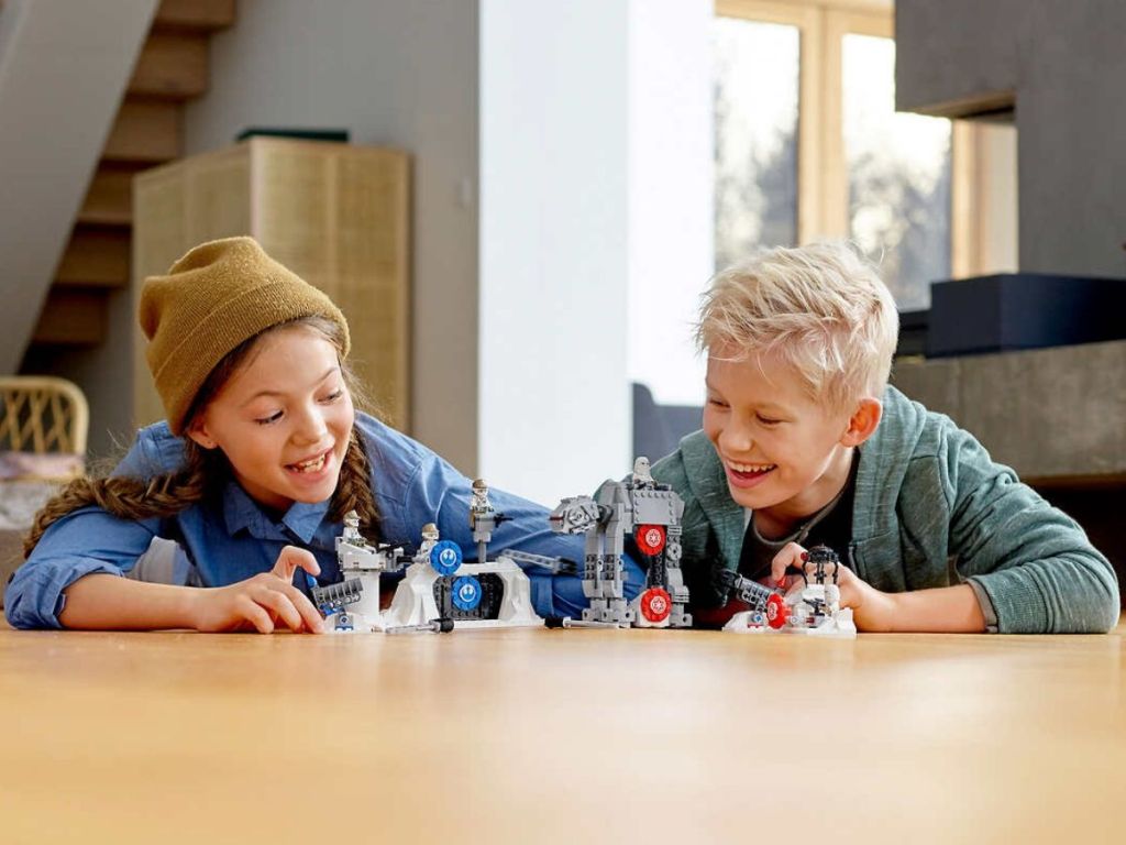two Kids playing with Star Wars Lego Set on wooden floor