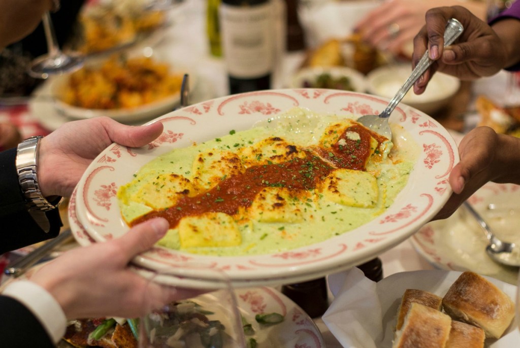 hand holding plate of italian food