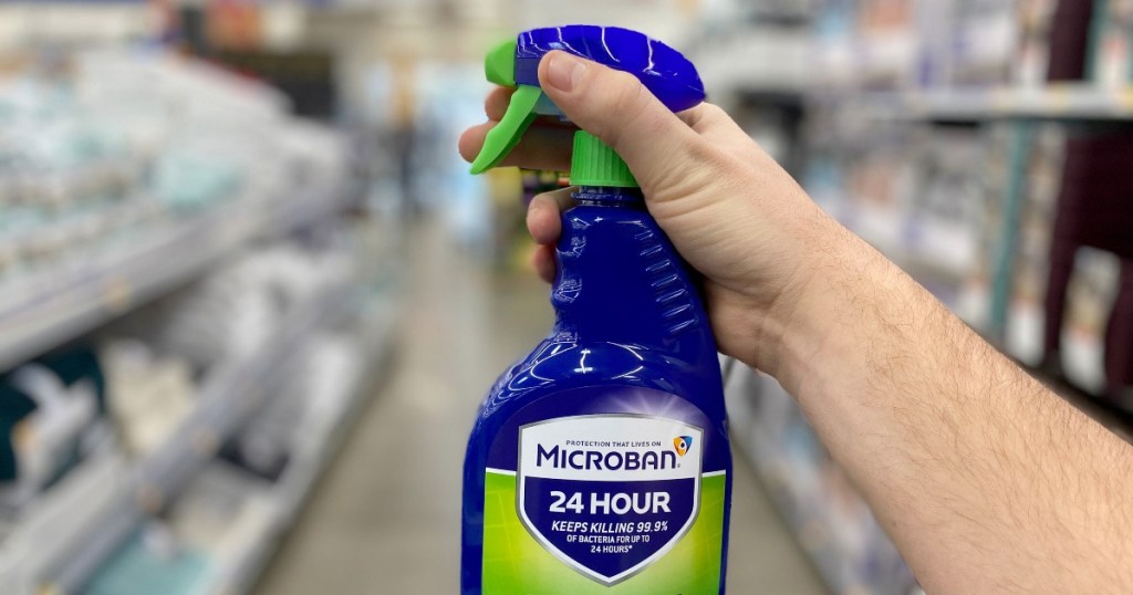 person holding up a blue bottle of microban disinfectant spray