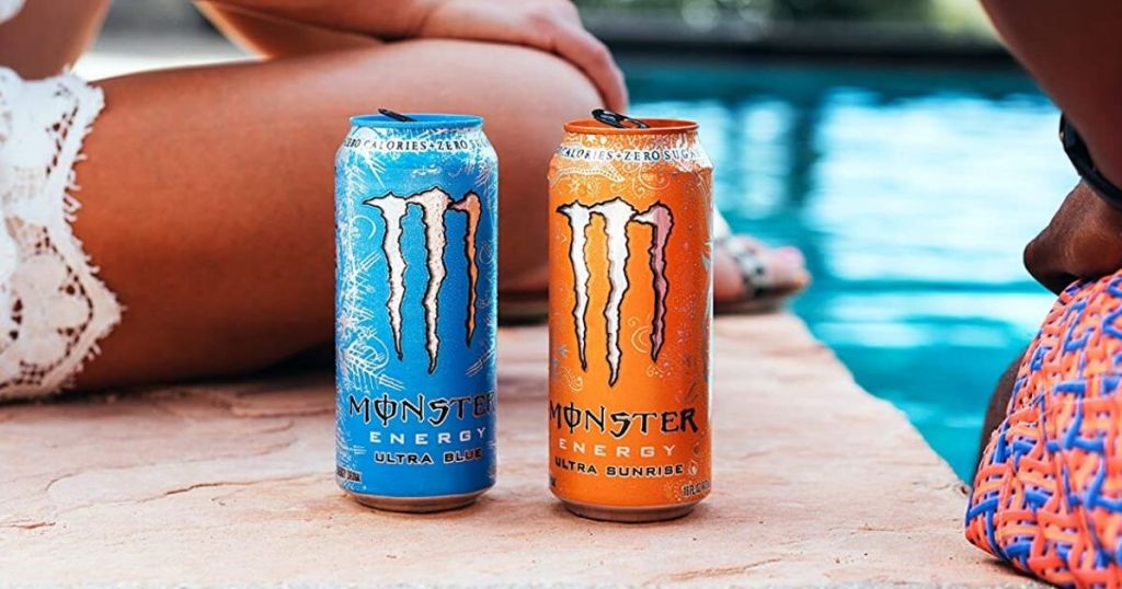 two monster energy drinks on the edge of a pool between a man and a woman