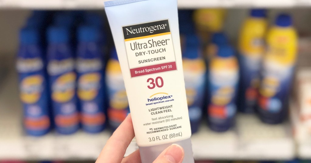 person holding up white and blue bottle of neutrogena sunscreen