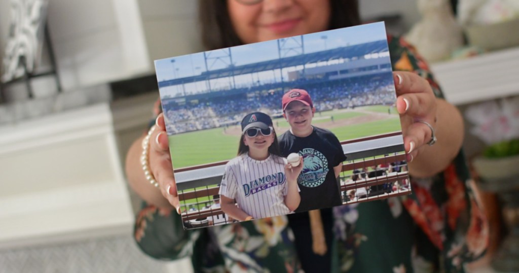woman holding photo of children at baseball game